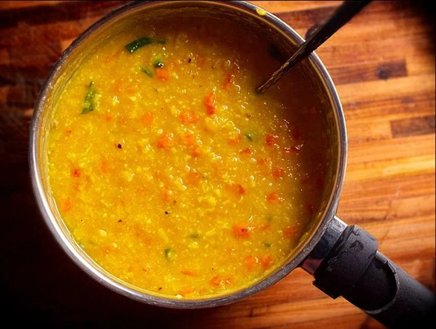 Bowl of Oats Khichdi garnished with fresh vegetables and herbs